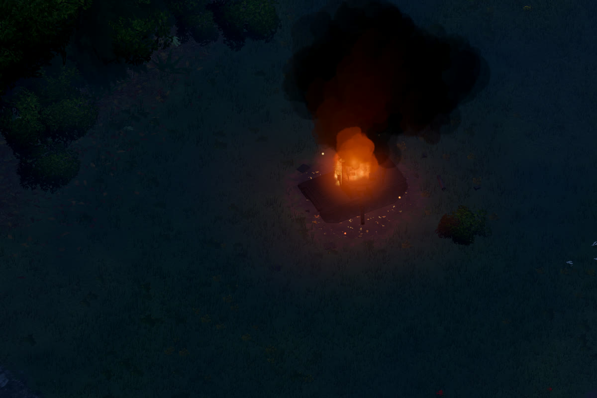 Ein Panzerwrack brennt nachts auf einer Wiese; das Feuer leuchtet die dunkle Rauchsäule darüber von unten orange an.